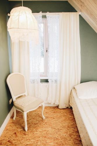 a bedroom with a white chair and a window at Loovälja Guesthouse in Limu