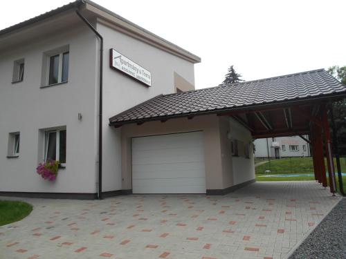a white house with a garage with a sign on it at Apartmán u Toma in Frýdlant nad Ostravicí