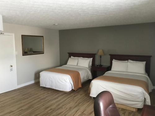 a hotel room with two beds and a chair at The Auberge Inn in New Liskeard