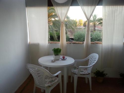 een witte tafel en stoelen in een kamer met een raam bij Sun & Palm Trees in Balsares