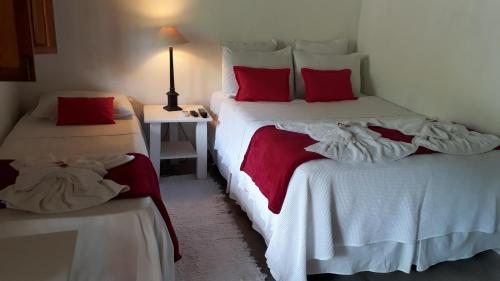 a bedroom with two beds with white and red pillows at Pousada João Maria in Trancoso