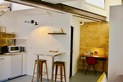 eine Küche mit einem Tisch und einigen Hockern in der Unterkunft Joli studio avec terrasse-jardin sur les toits, coeur historique in Montpellier