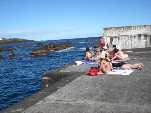 a group of people sitting on a dock near the water at PICO HOLIDAY RENTALS, Casa Do Avô Faidoca in Calheta de Nesquim