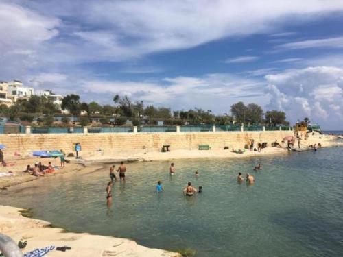 a group of people in the water at a beach at Ocean View, Apartment 1 in Marsaskala