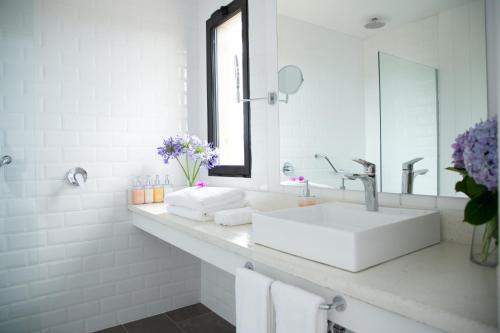 a white bathroom with a sink and a mirror at Casa Flor in Punta del Este