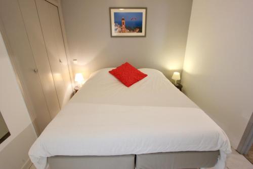 - une petite chambre avec un lit blanc et un oreiller rouge dans l'établissement Fauvettes Sea Cannes, à Cannes