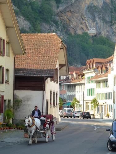 a man riding a horse drawn carriage down a street at Post Hardermannli in Interlaken