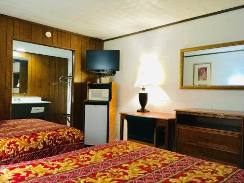 a hotel room with two beds and a desk and a television at Granada Inn Motel - Kalkaska in Kalkaska