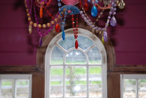 a bunch of beads hanging from a window at Freshwaterfarm Cottages - Muriwai in Waimauku