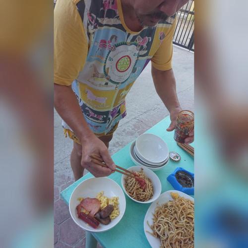 a man preparing food on a table with noodles at Prince Transient house in San Jose