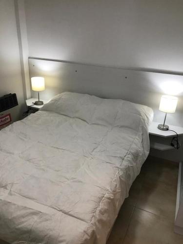a bedroom with a white bed with two lamps at Departamento Leben in Colón