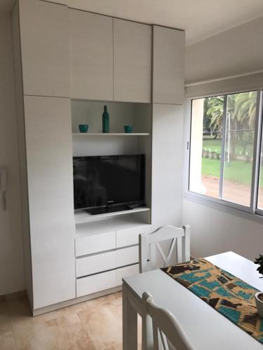 a white kitchen with a flat screen tv and a table at Departamento Leben in Colón