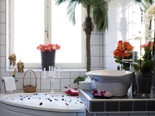 a bathroom with a bath tub with flowers on the counter at Hotell Läckö in Lidköping