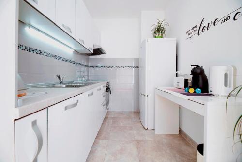 uma cozinha branca com uma pia e uma geladeira em Apartment DORA Split em Split