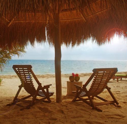two chairs and a table under a straw umbrella on the beach at Margarita del Sol Hotel Costa Maya in Mahahual
