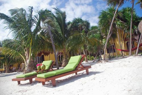 two green lounge chairs on a beach with palm trees at Margarita del Sol Hotel Costa Maya in Mahahual