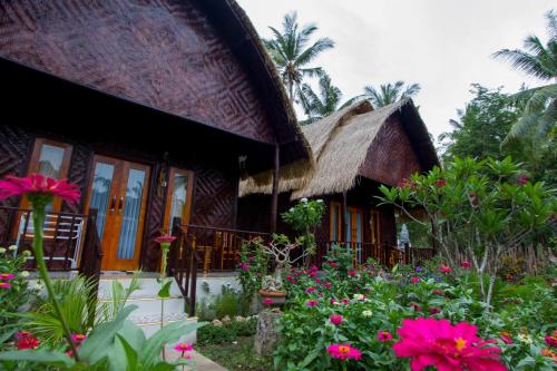 a house with a thatched roof and a garden with flowers at Kubu Artha Bungalow Nusa Penida in Nusa Penida