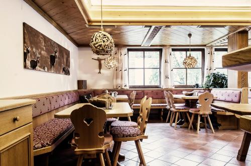 ein Restaurant mit Tischen, Stühlen und Fenstern in der Unterkunft Atelier Garni Astei in Großarl