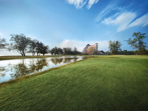 un parcours de golf avec un lac et un bâtiment dans l'établissement Resorts World Kijal, à Kijal