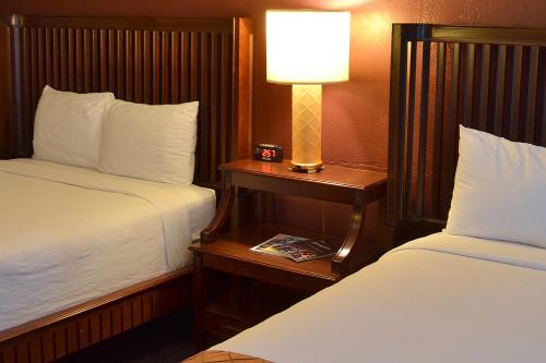a hotel room with two beds and a lamp on a table at Cascades Inn in Bloomington