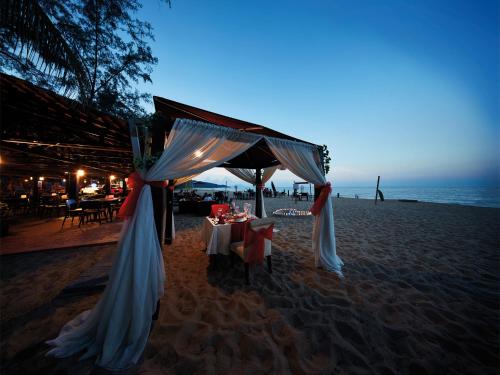 uma mesa de jantar na praia à noite em Resorts World Kijal em Kijal