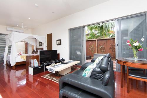 a living room with a black leather couch and a television at Kia Orana Villas and Spa in Rarotonga