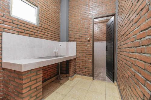 Un baño con lavabo y pared de ladrillo. en RedDoorz Plus At Ampera Raya, en Yakarta