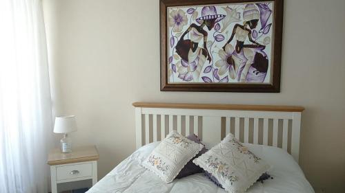 a bed with two pillows and a painting above it at Condominio Arena Maris in Algarrobo