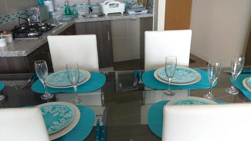 a dining room table with blue plates and wine glasses at Condominio Arena Maris in Algarrobo