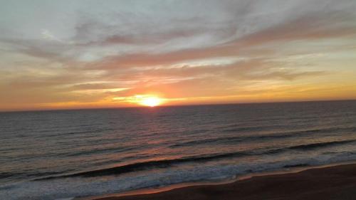 a sunset on the beach with the ocean at Condominio Arena Maris in Algarrobo
