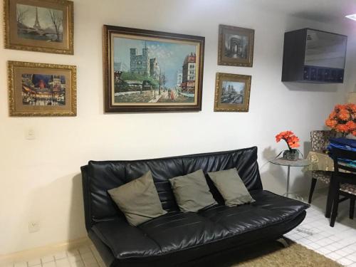 a black leather couch in a living room with pictures on the wall at TOTAL Mar in Niterói