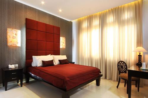 a bedroom with a large red bed and a desk at The Radiant Hotel in Kuta