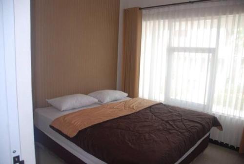 uma cama com duas almofadas e uma janela num quarto em Resort Faza em Garut
