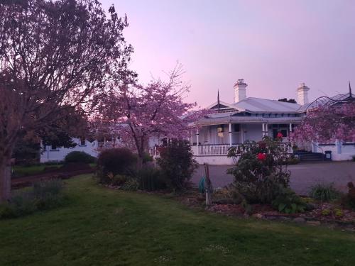a white house with a porch and a yard at Lancewood Lodge in Bulls