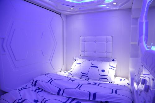 a bedroom with a bed in a room with purple lighting at Dormitos in Manila