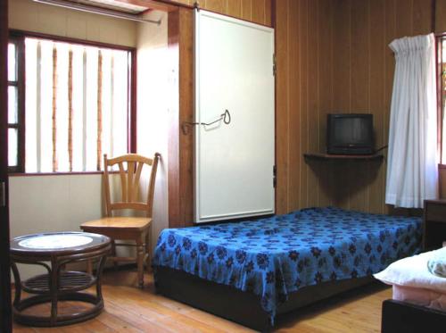1 dormitorio con 1 cama, 1 silla y TV en Minshuku Rakutenya, en Ishigaki Island