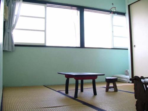 a table in a room with two large windows at Minshuku Rakutenya in Ishigaki Island