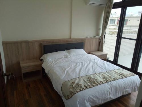 a bedroom with a white bed with a window at Bigger B&B in Jinning