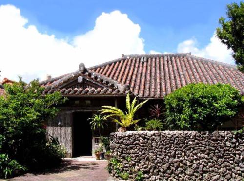 una casa con una pared de piedra delante de ella en Minshuku Rakutenya, en Ishigaki Island