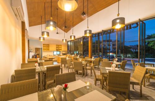 a restaurant with tables and chairs and windows at Cher​mantra​ Aonang​ Resort & Pool​ Suite in Ao Nang Beach