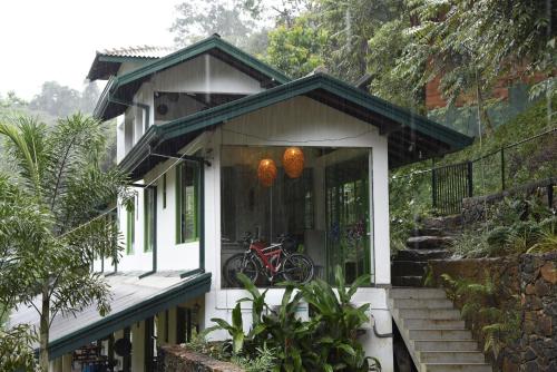 a house with a bike on the front of it at Sinharaja Forest Edge in Deniyaya