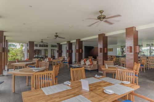 a restaurant with wooden tables and chairs and a ceiling fan at The Samaya Ubud in Ubud