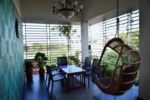 a room with a table and chairs and windows at Mango Tree Homestay in Hampi