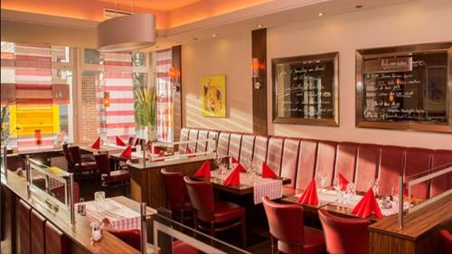um restaurante com guardanapos vermelhos em mesas e cadeiras em Dithmarscher Hof em Itzehoe