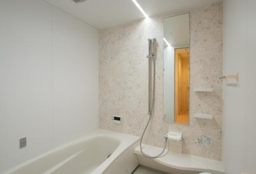a white bathroom with a tub and a mirror at North Star Hirafu in Niseko