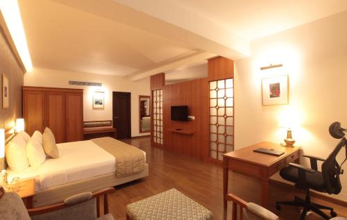 a hotel room with a bed and a desk and a television at Monsoon Empress Kochi in Cochin