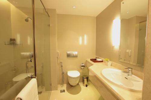 a bathroom with a sink and a toilet and a shower at Monsoon Empress Kochi in Cochin