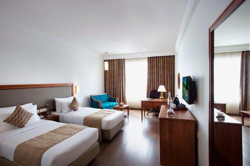 a hotel room with two beds and a television at Monsoon Empress Kochi in Cochin