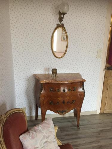 a wooden dresser with a mirror on a wall at Chez Mémère Hélène in Sormonne