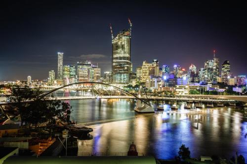 a city skyline at night with a bridge over a river at River Plaza Apartments Brisbane Southbank in Brisbane